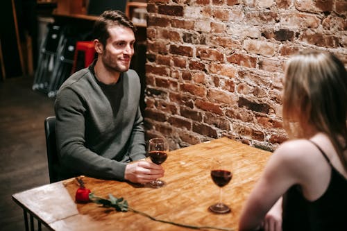 Uomo In Maglione Grigio Seduto Accanto Al Tavolo In Legno Marrone