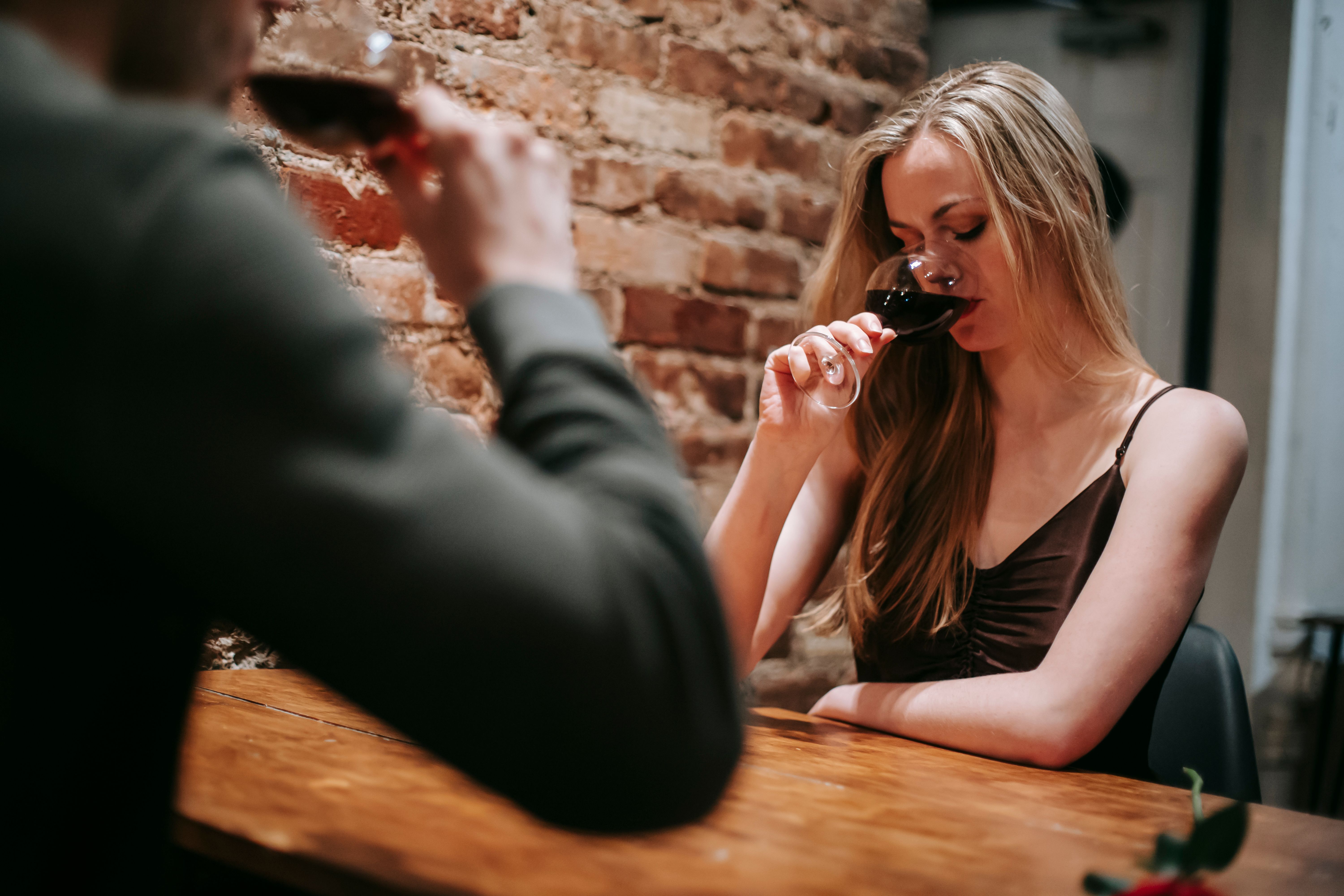 Free Low angle of young couple enjoying red wine sitting at table in restaurant Stock Photo