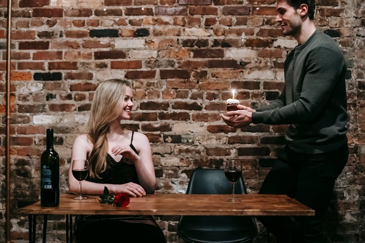 Couple Celebrating Birthday With Cupcake In Restaurant