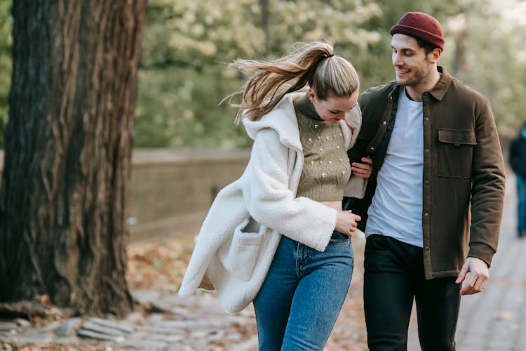 Positive Couple Walking In Park In Autumn