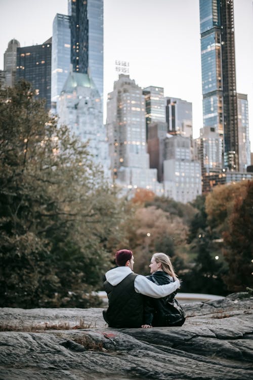 Anonymous couple hugging while sitting on stony ground in park