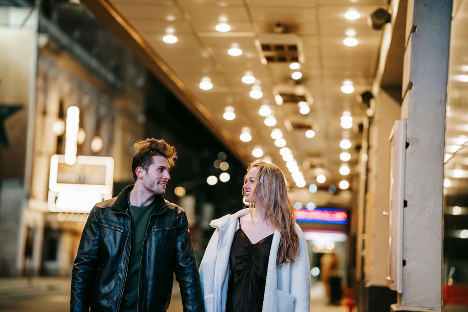 A couple smiling at each other while walking home after a date