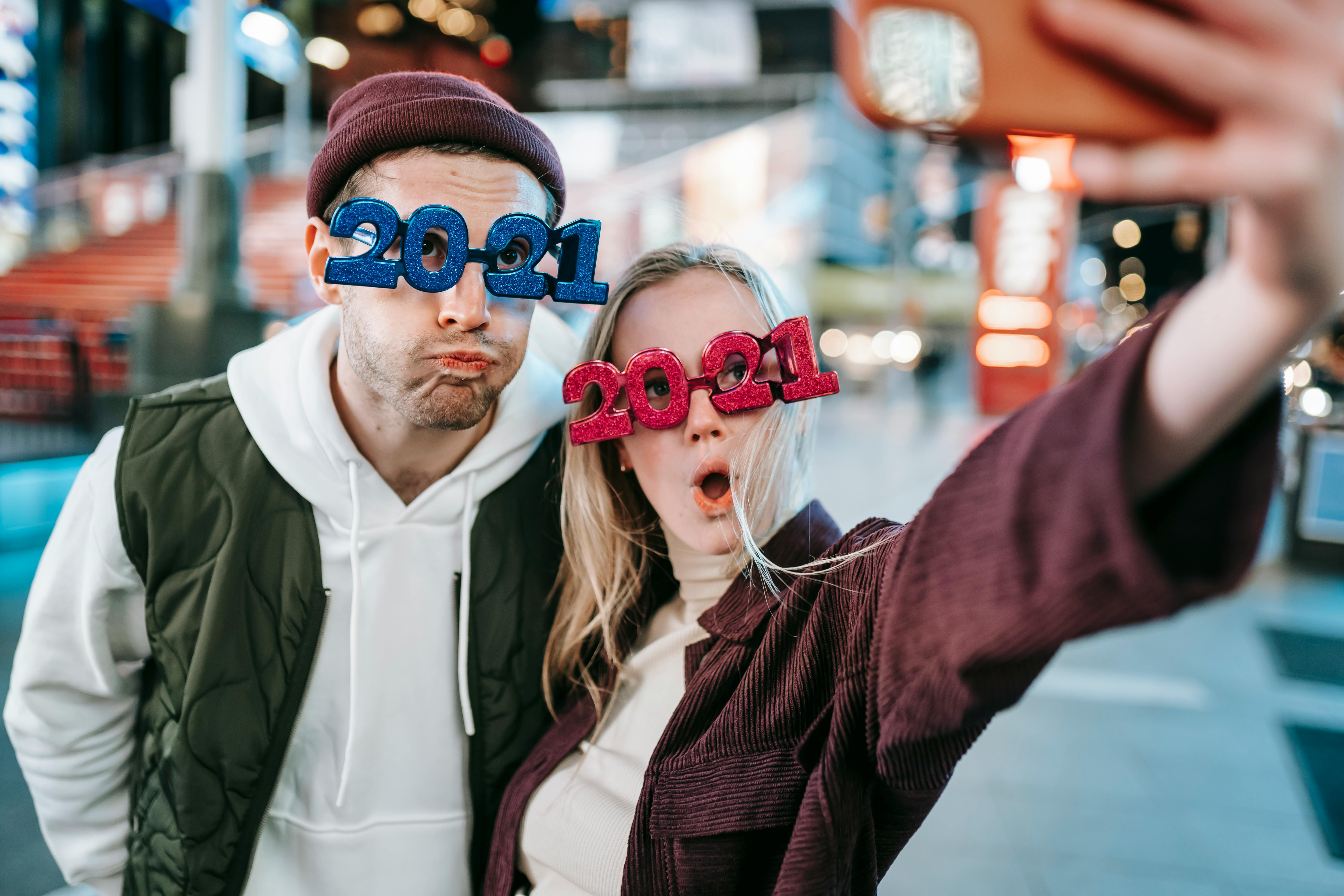 funny couple in decorative festive glasses taking selfie on street