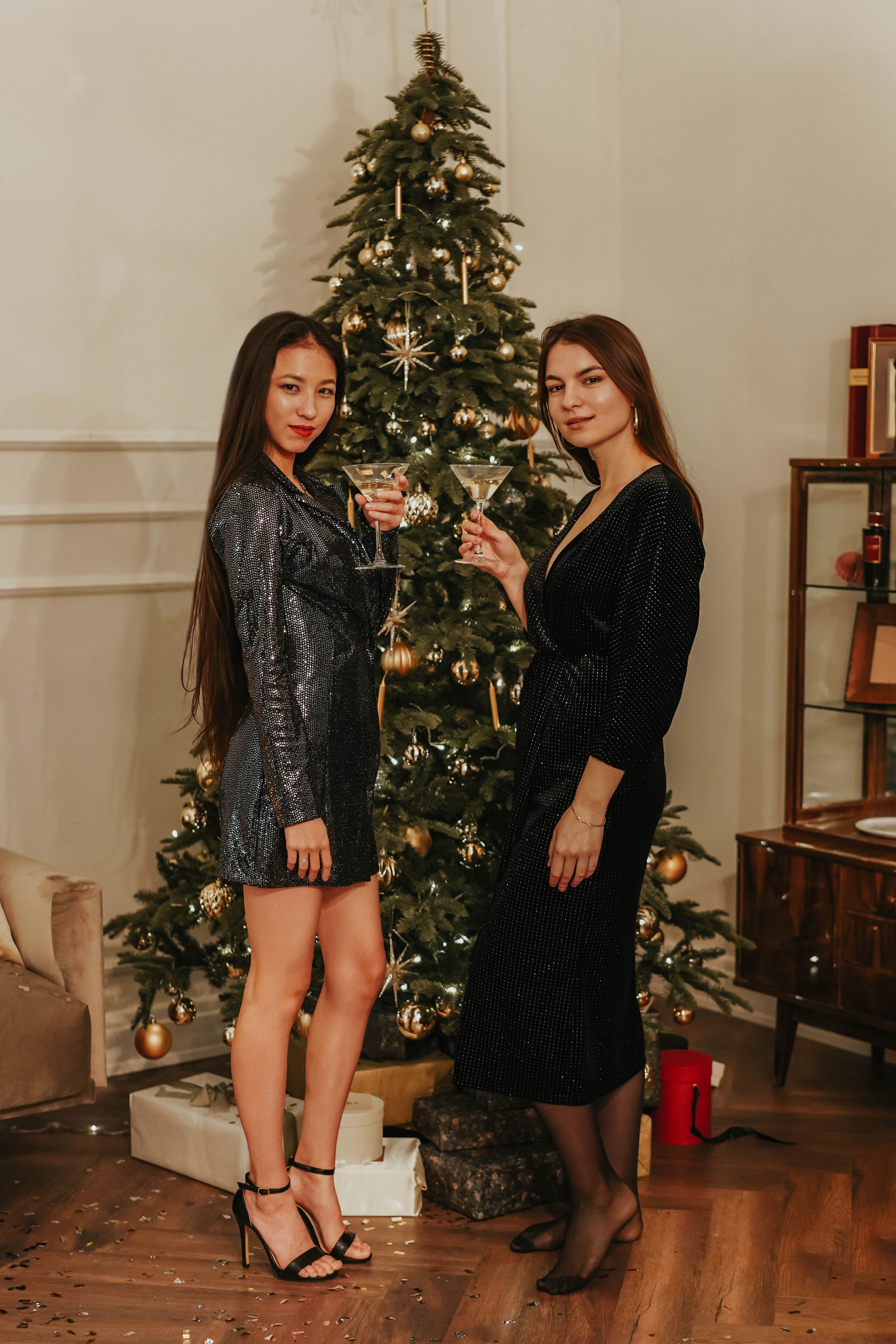 两位女士在圣诞树旁喝着香槟，享受时尚的新年派对