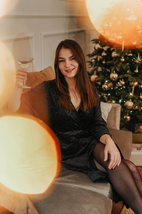 Woman In Black Long Sleeve Dress Sitting On A Couch