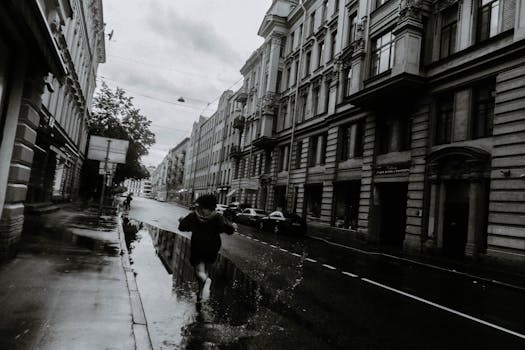 A person running through a rainy city street, captured in motion in black and white.