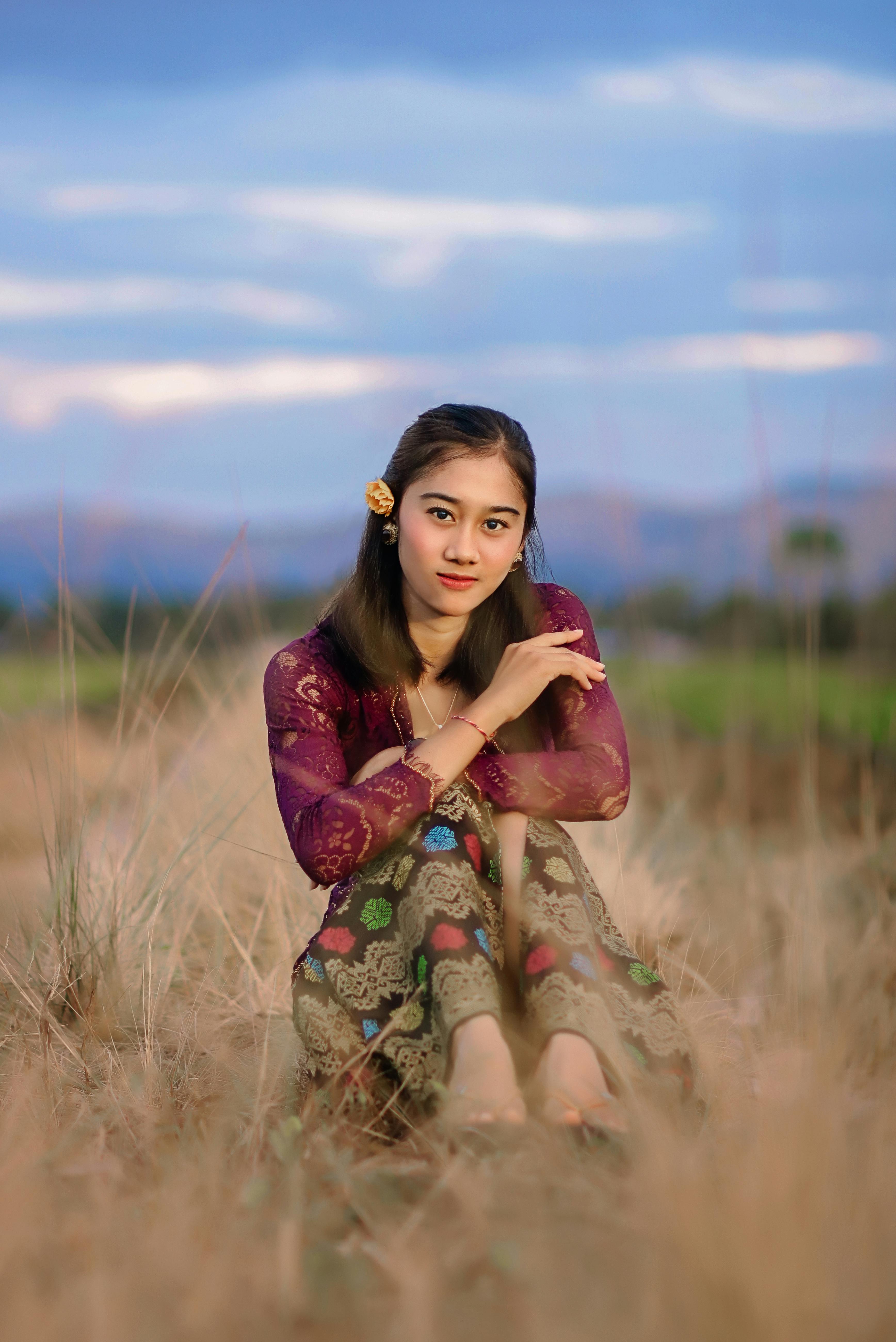 woman in long sleeve dress sitting on brown grass field