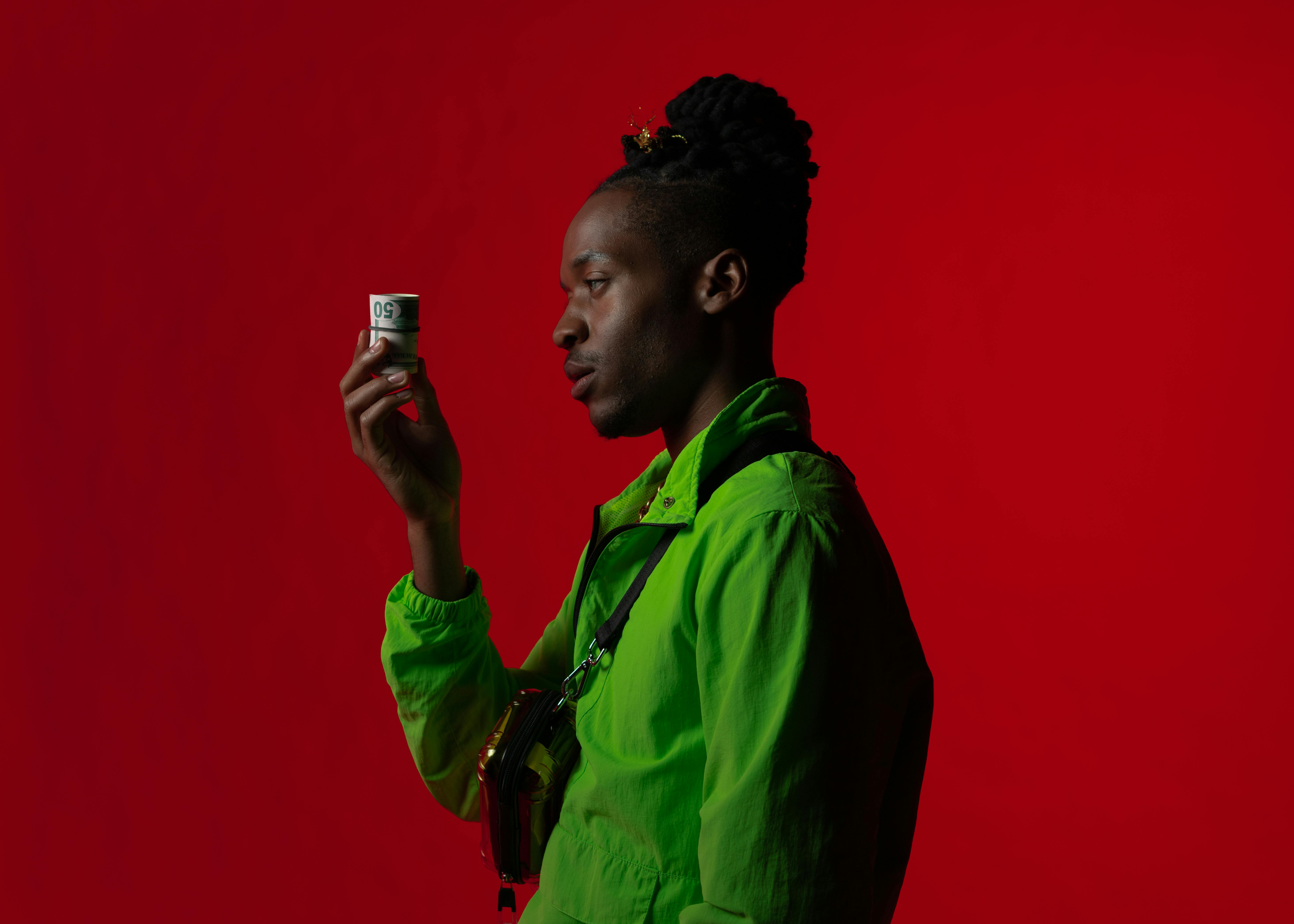 man in green button up shirt holding rolled banknotes