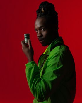 Profile of a man in a green jacket holding money with a red backdrop.