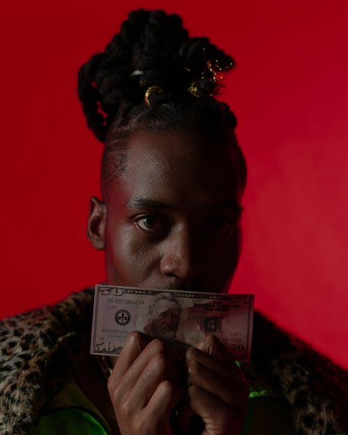 Man with Dreadlocks Looking at Camera Holding Us Dollar Bill