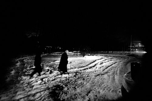 Free Black and white of silhouettes of anonymous person walking on snowy road in winter night Stock Photo