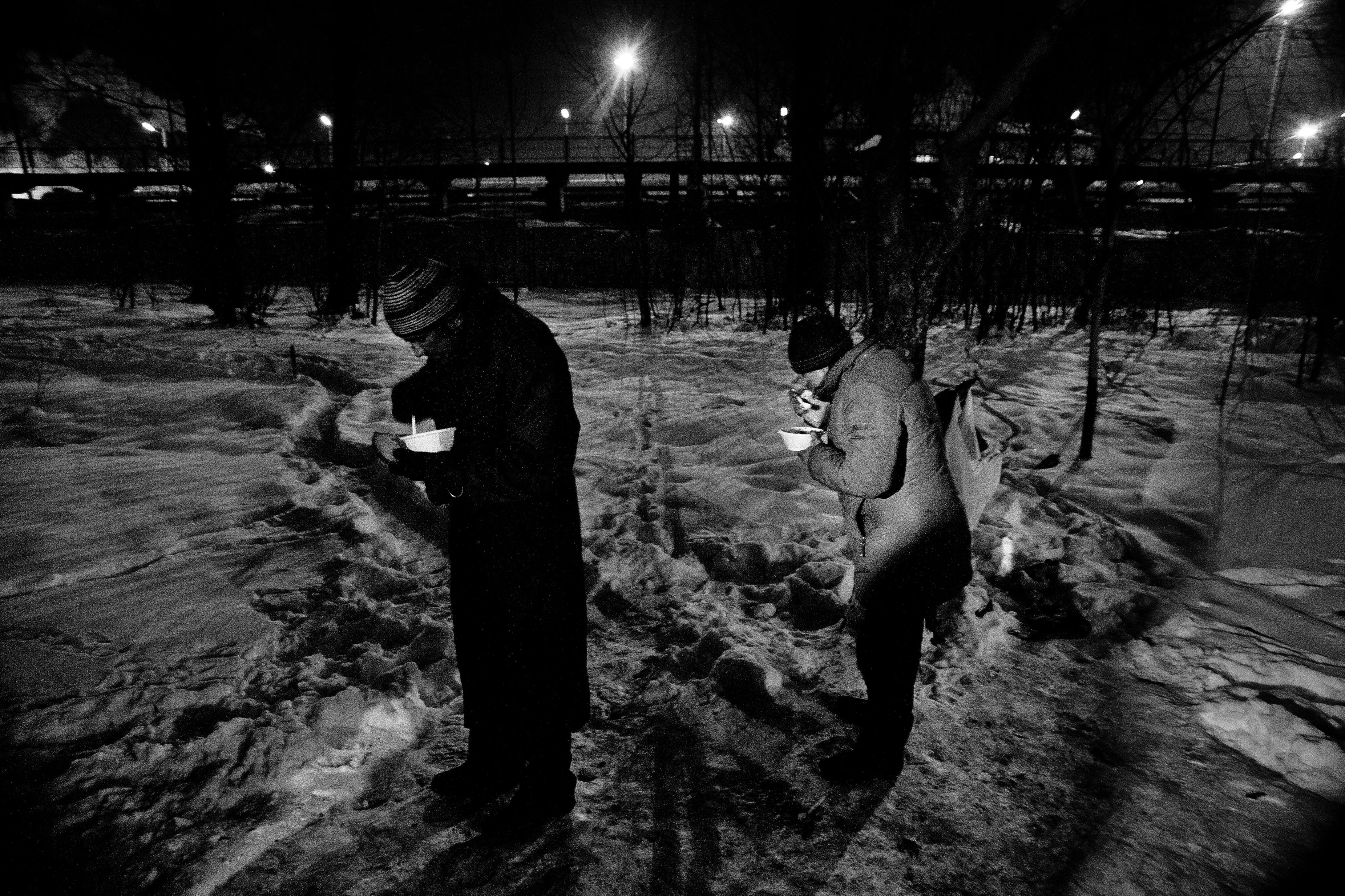 homeless people eating food in winter park