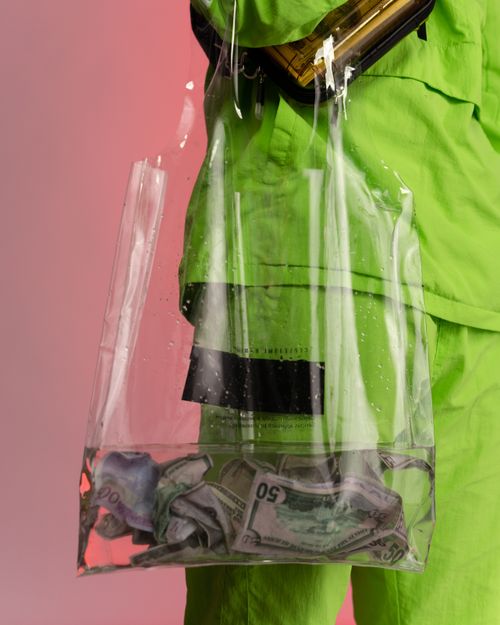 Free Close-up of US dollars soaked in a clear plastic bag held by a person in a green outfit. Stock Photo