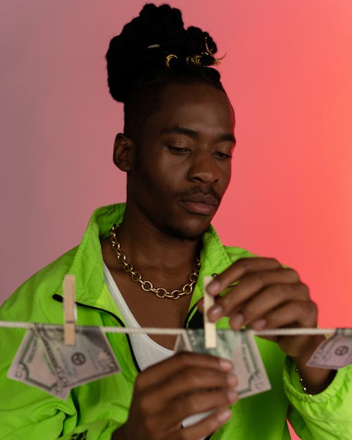 Man in Green Jacket Hanging Wet Banknotes on the Clothes Line