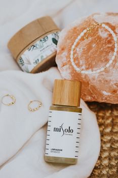 Elegant flat lay showcasing skincare product, bracelet, and crystals.