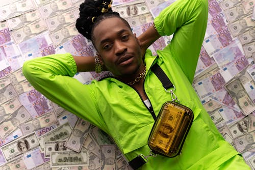 Free Man in Green Jacket Lying Down on Money Stock Photo