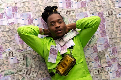 Man in Green Jacket Lying Down on Money