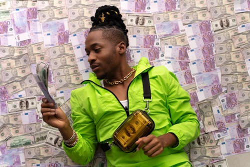 Man in Green Jacket Lying Down on Money
