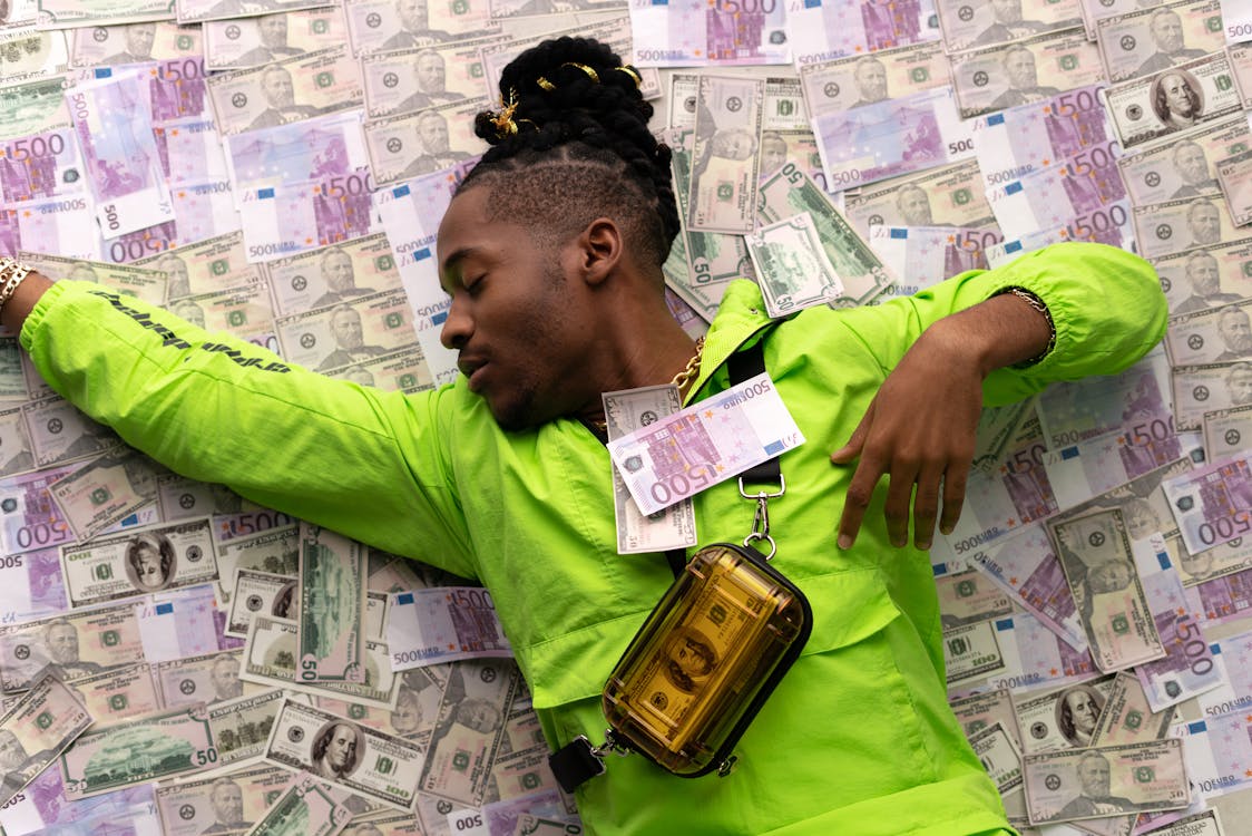 Free Man in Green Jacket Lying Down on Money Stock Photo