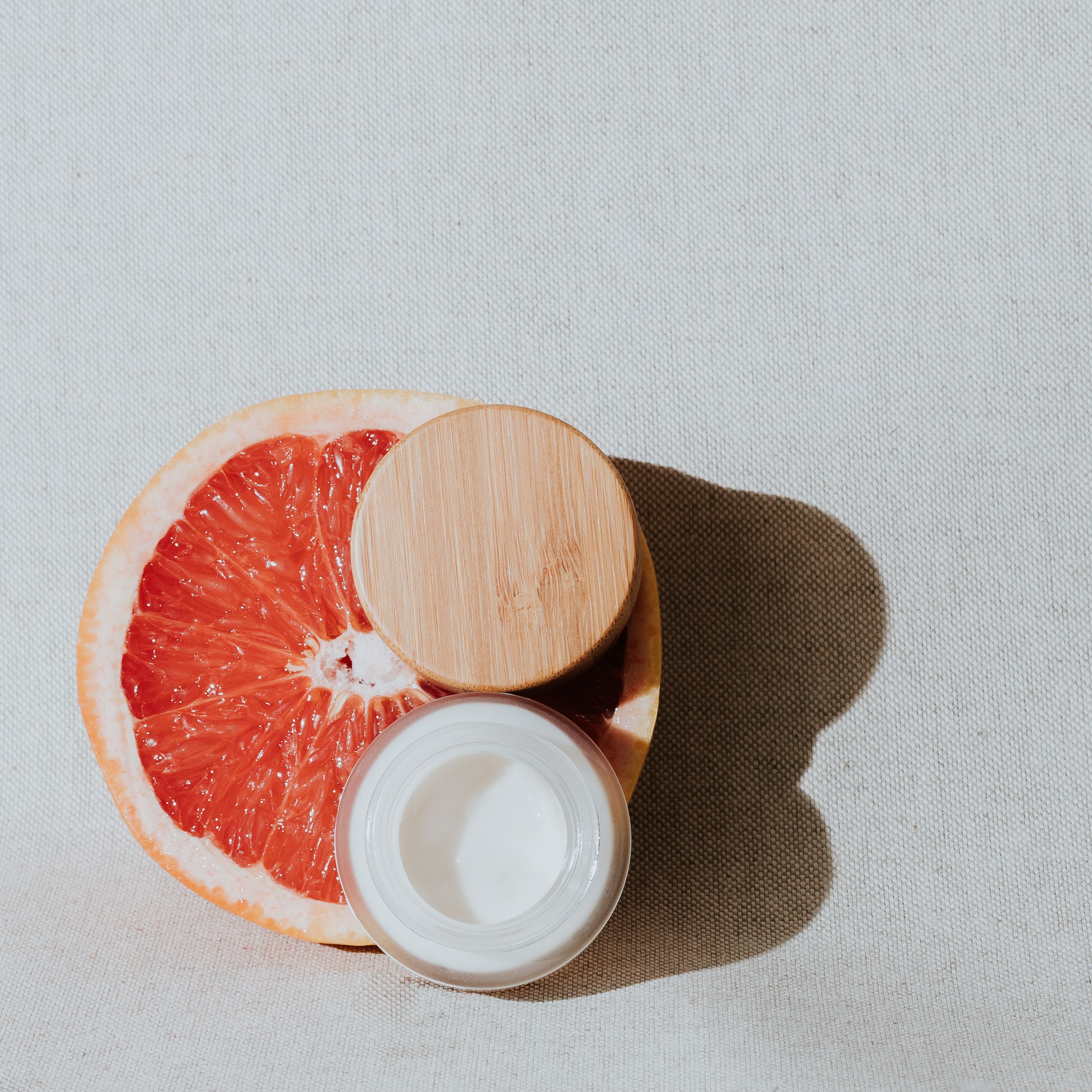 Opened Cream Container and Lid on a Sliced Grapefruit