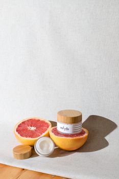 A luxury skincare cream jar set alongside fresh grapefruit, emphasizing organic beauty and freshness.