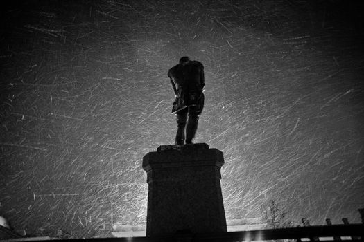 Stone statue in snowy water at night