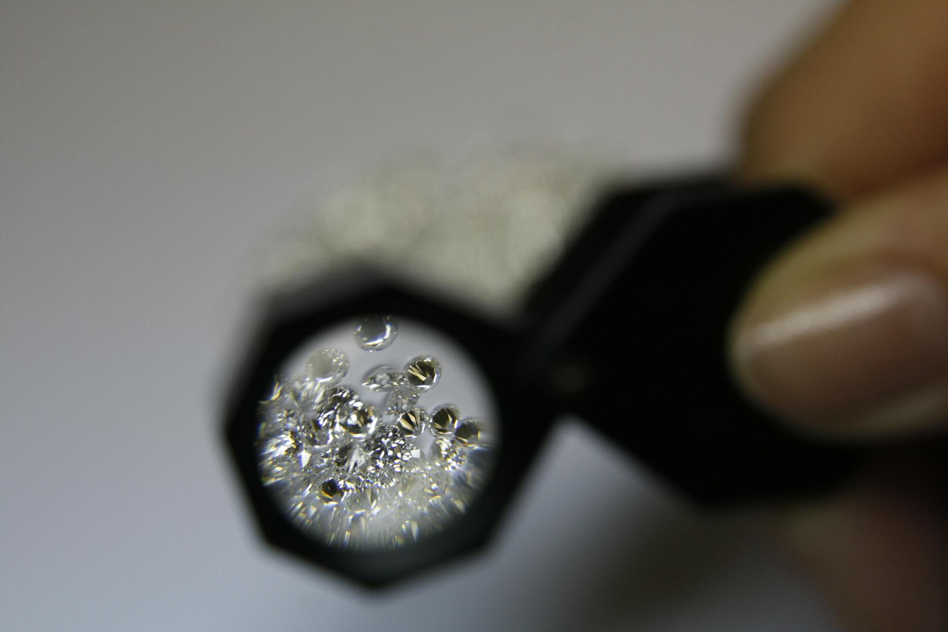 Detailed view of diamonds examined with a jeweler's loupe for quality assessment.