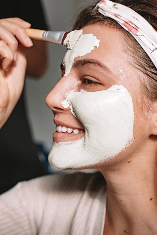 Woman Applying Face Cream Using Wooden Brush