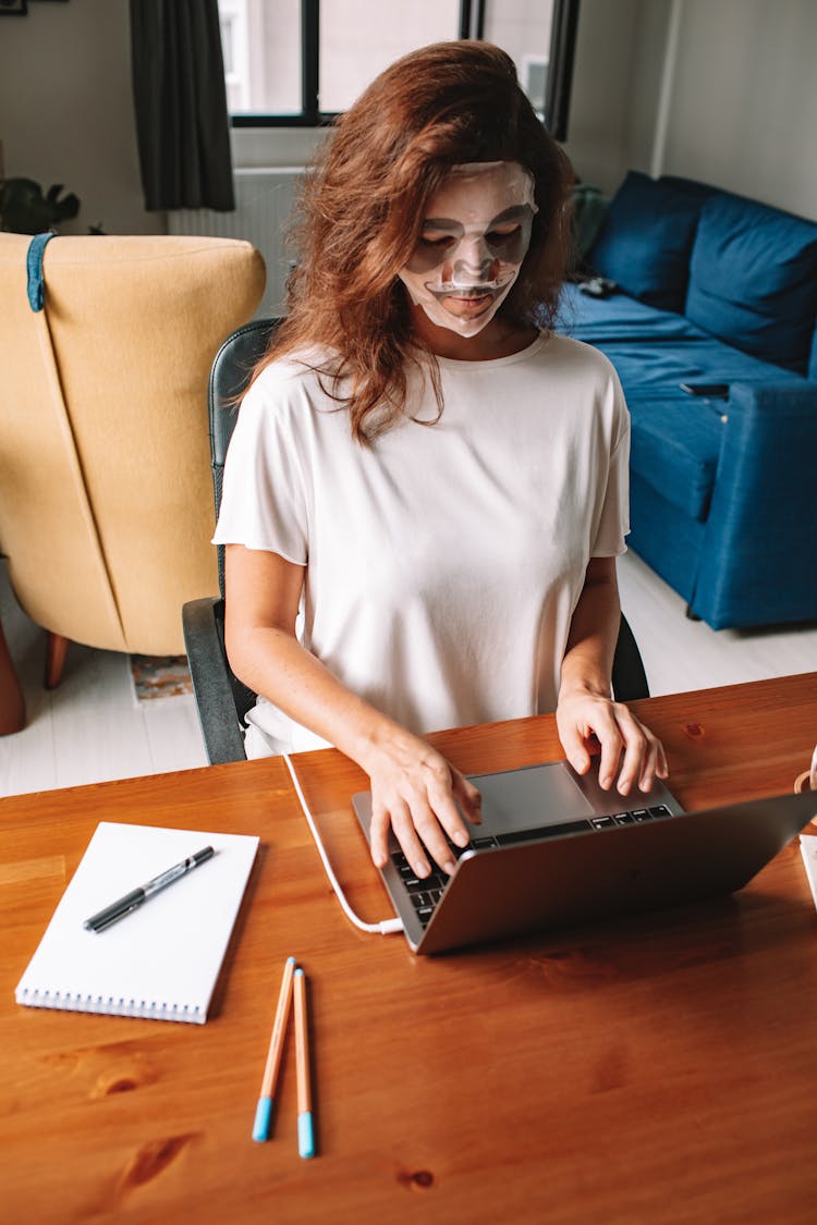 Woman In Beauty Mask Working On Laptop From Home