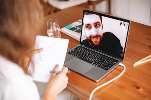 Free Woman on Video Call to a Man in the Laptop Screen Wearing Facial Mask Cream Stock Photo