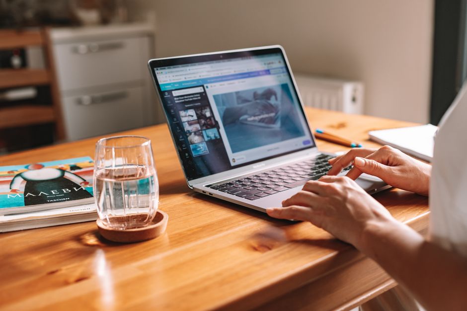 Does an Automatic Cat Water Fountain Actually Keep Cats Hydrated Better? Close-up of hands on a laptop in a cozy home office with a water glass on desk.