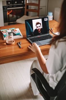 Woman having a video call on a laptop in a cozy home office.