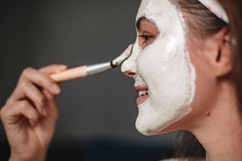 Woman Smiling While Applying Facial Cream 