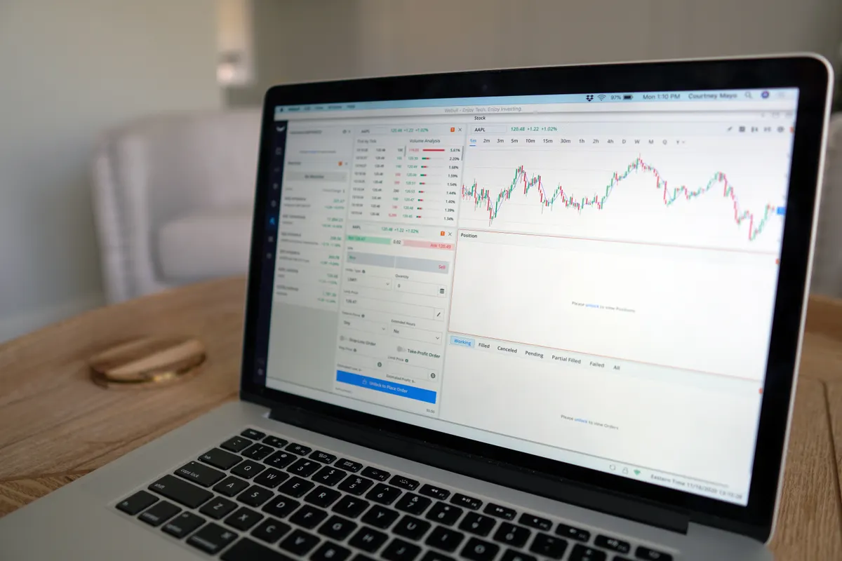 Laptop showing stock charts, analyzed by an AI seo writing assistant for data-driven blog posts.