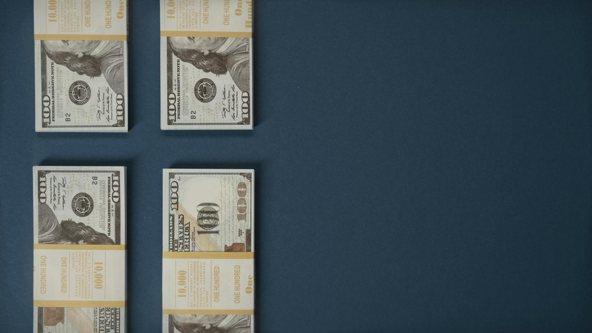 Bundles of US dollar bills neatly stacked on a blue surface, showcasing wealth and finance.