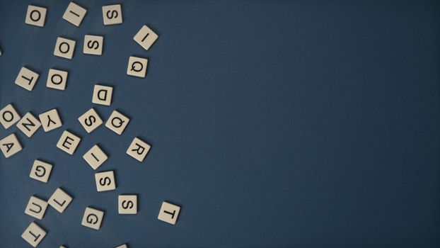 Scrabble tiles scattered on a blue background with ample copy space.