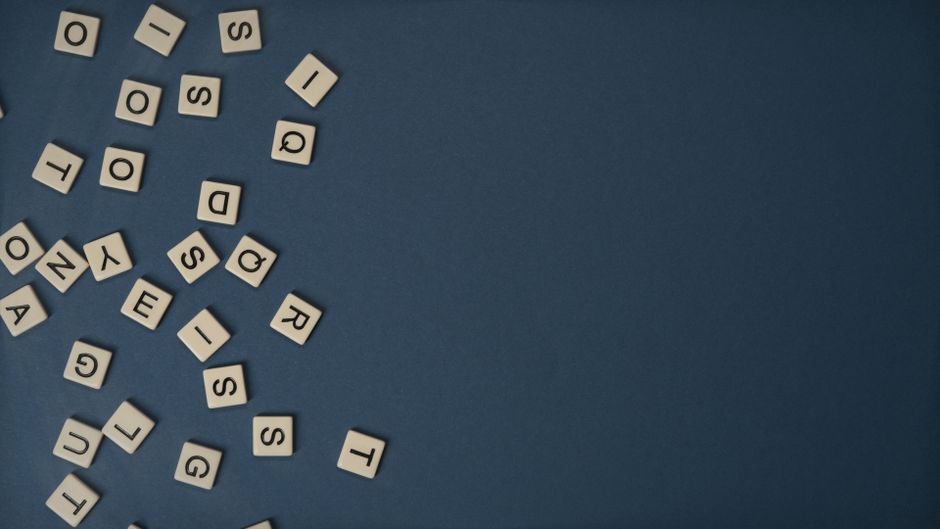 Scrabble tiles scattered on a blue background with ample copy space.