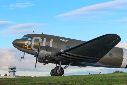 Iconic WWII Douglas C-47 Skytrain aircraft displayed with a radio tower in the background.