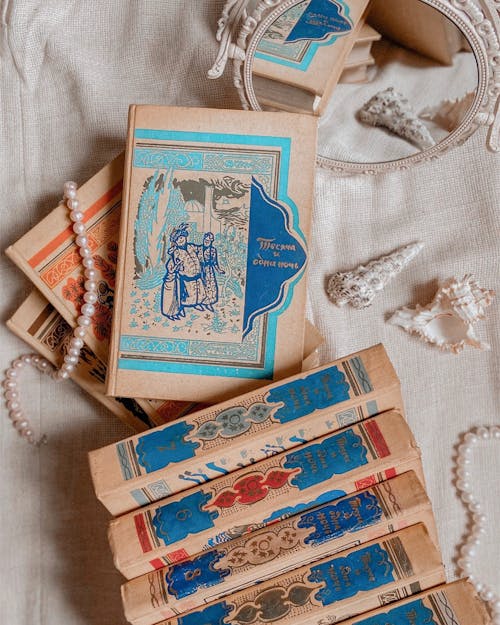 Old books placed on table near mirror and shells