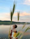 Cereal grass against woman standing on shore of lake