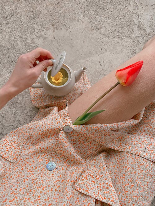 Woman with teapot with flower tea and tulip