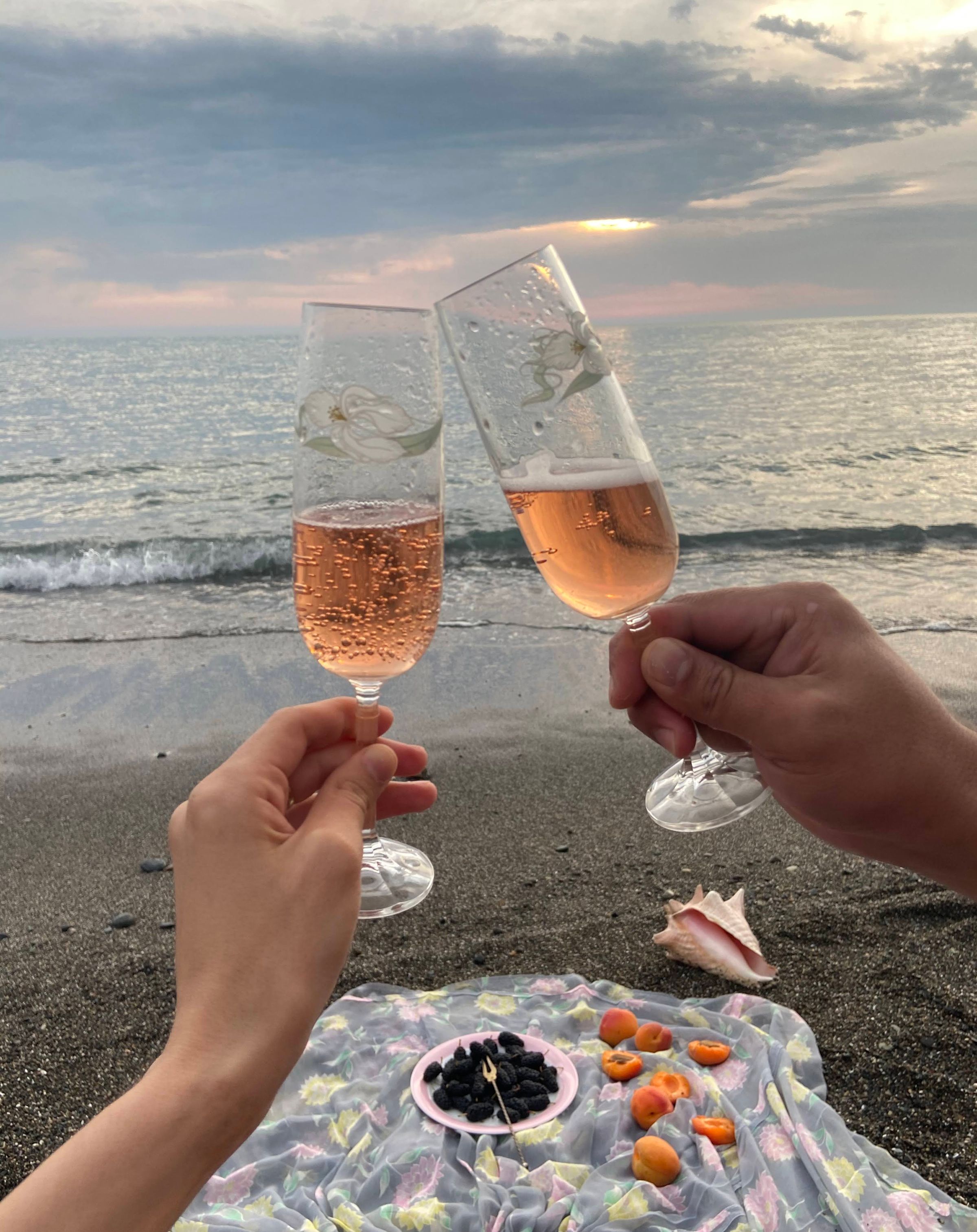 A couple clinking champagne glasses on the seashore