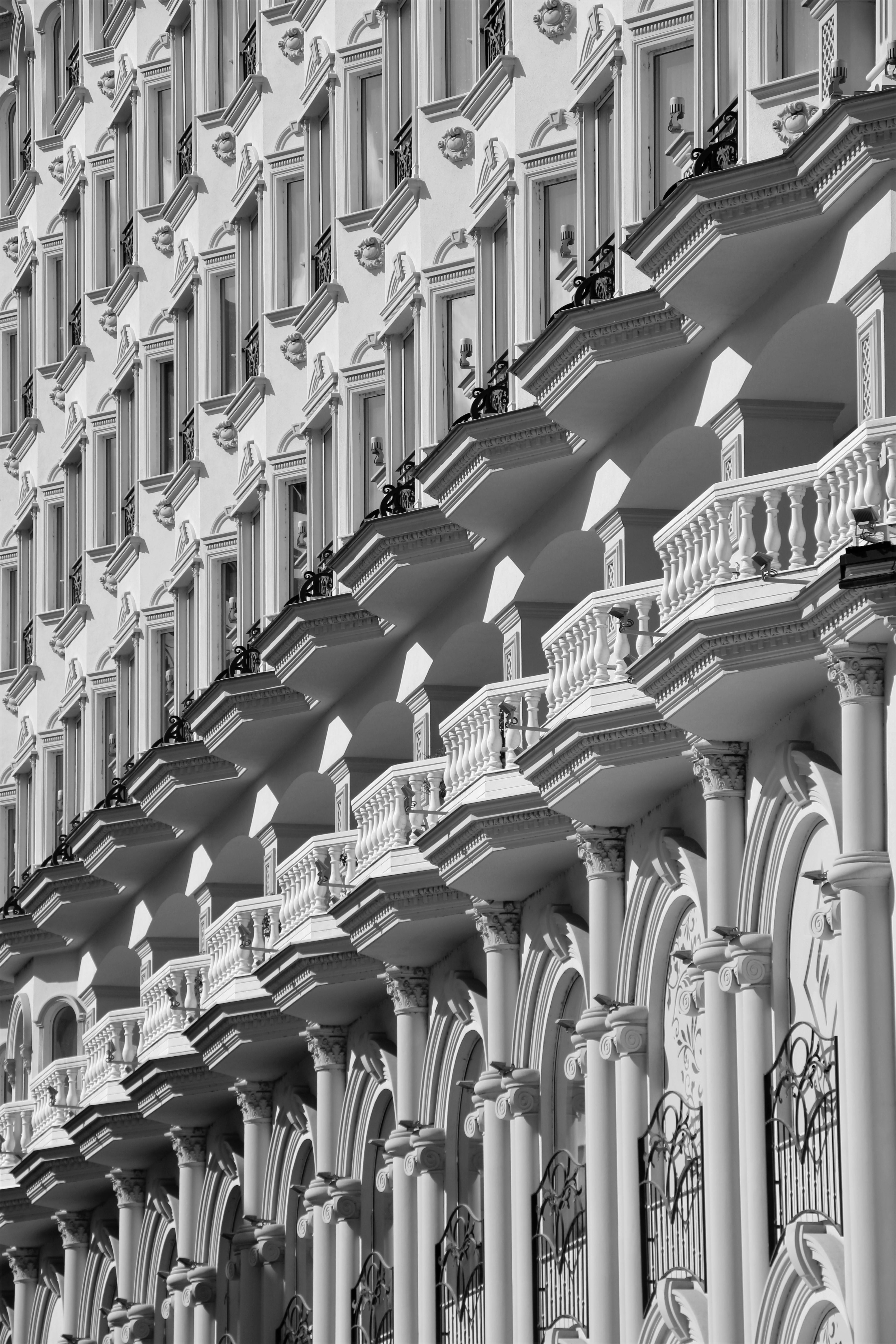 A detailed black and white view of an ornate building facade in Skopje, showcasing its neoclassical balconies and arches.