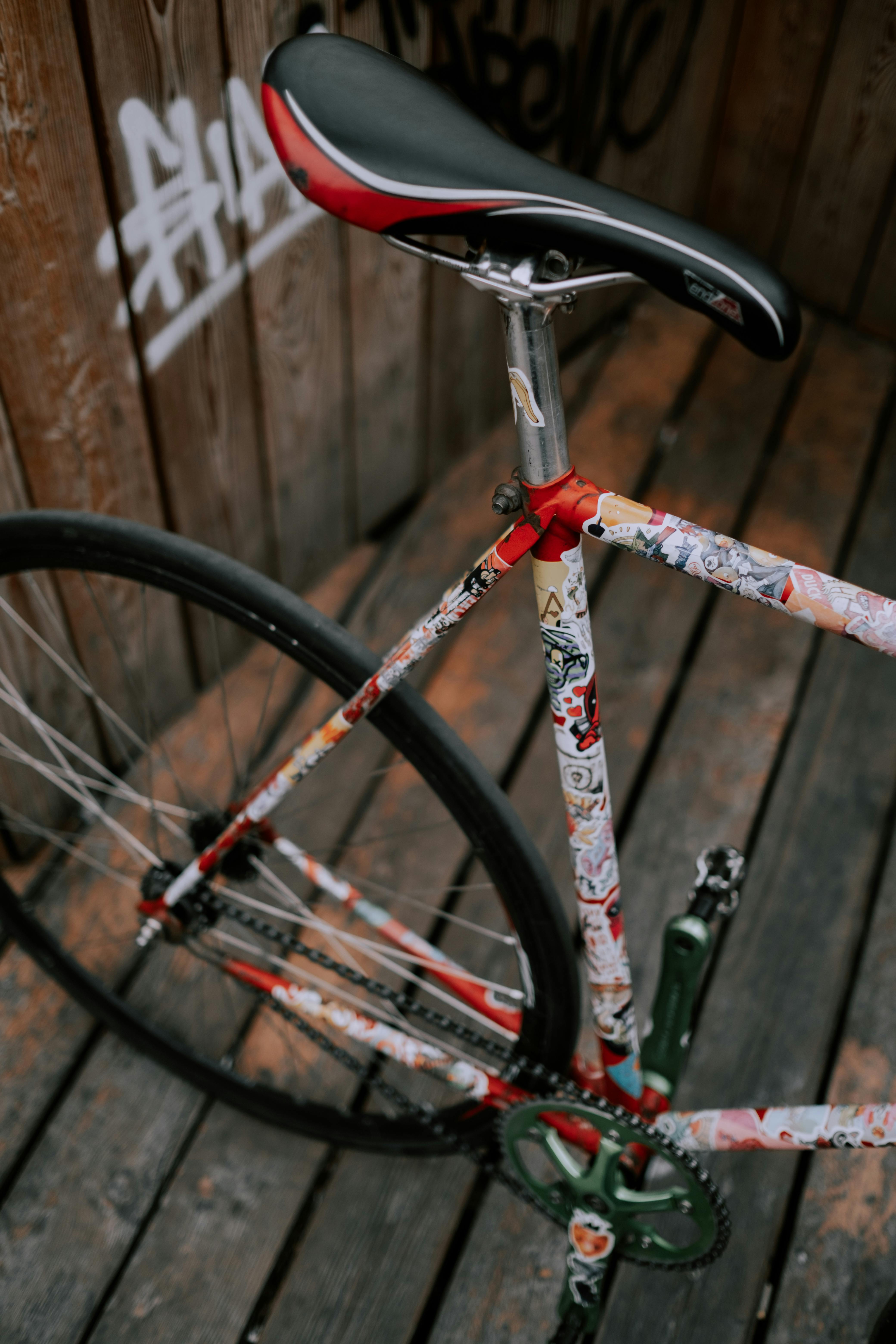 Close-up of a custom fixie bicycle with vibrant decor on a wooden deck.