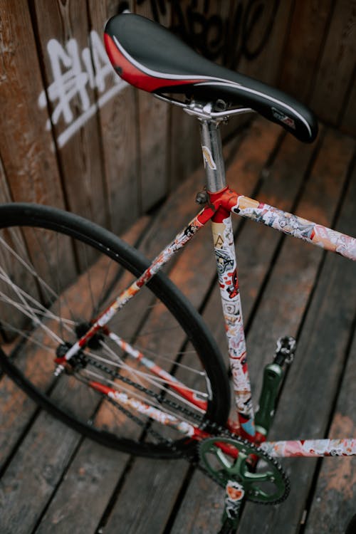 無料 茶色の木製のフェンスの近くの赤と黒の自転車 写真素材