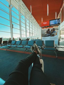 Crop anonymous male traveler with luggage waiting for departure in waiting room of modern airport