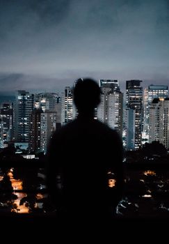 黄昏时分，一个人的轮廓映衬在现代城市的天际线上，展现出充满活力的城市氛围