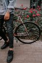 Person in Denim Jacket and Denim Jeans Standing Beside the Bicycle