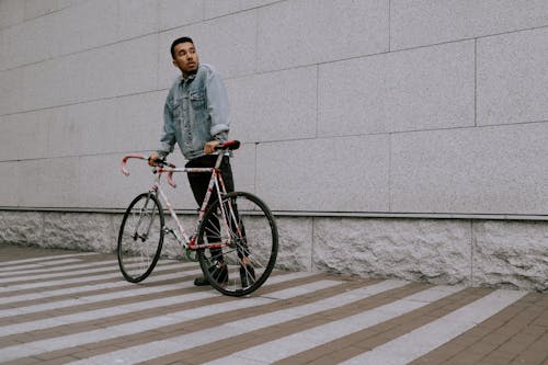 Mulher De Jaqueta Jeans Azul Em Pé Ao Lado Da Bicicleta Vermelha