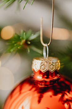Close-up of a red Christmas ornament hanging on a decorated tree, exuding festive cheer.